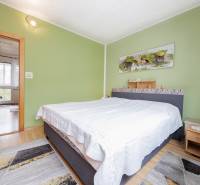 A bedroom in a 3-room apartment with a green wall and a wooden decor floor.