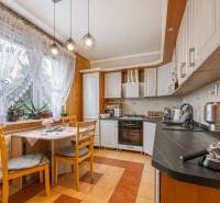 A kitchen in a 3-room apartment with soft lighting, flowers, and delicate curtains.
