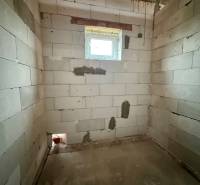 An unfinished room with a concrete floor and a window in a family house.