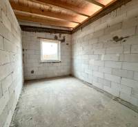 An unfinished room in a family house with a concrete floor and a window offers space for completion.