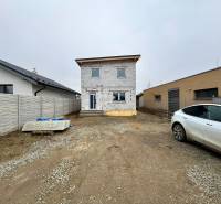 The construction process of a family house on Hviezdna Street in Čaňa. Surrounding buildings and a car.