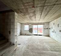 Unfinished interior of a family house with a view of the terrace through a large window.