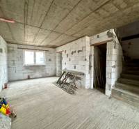 The interior of an unfinished family house with a concrete staircase and bare walls.