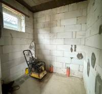 A building in a family house with an incomplete interior and an unfinished floor, with a window and machinery.