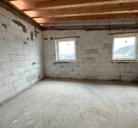 The interior of a family house with unfinished walls and a ceiling made of wooden beams.