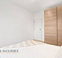 Bedroom in a 3-room apartment with a white wall, built-in wardrobe, and a red lamp.