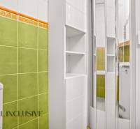 A bathroom with green tiles and a white cabinet in a 3-room apartment.