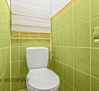 WC with a white toilet and green tiles in a 3-room apartment.