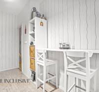 Dining area with a bar table and chairs, storage space, wooden decor flooring.