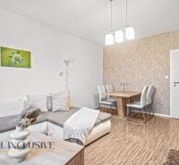 Living room with wood-patterned flooring, a sofa, and a dining table in a three-room apartment.