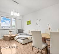 Living room in a three-room apartment with light-colored walls and a wooden decor floor.