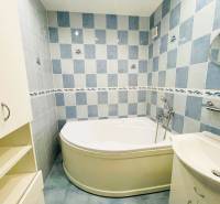 A bathroom with a built-in bathtub in a 3-room apartment with blue tiles and a sink.