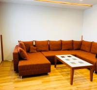 Living room with an orange sofa and a coffee table in a three-room apartment.