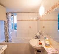 Bathroom in a 2-room apartment with a bathtub, white tiles, and a mirror.