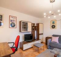 Living room in a two-room apartment with a wooden decor floor, decorated with paintings and furniture.