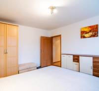A bedroom in a 2-room apartment with wooden decor and furniture in light shades.