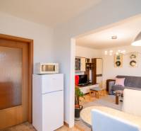 Interior of a 2-room apartment with a room featuring a sofa, microwave, and decorative pictures on the wall.