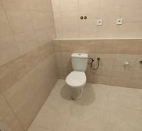 Bathroom in a 2-room apartment with a toilet and tiles with a beige decor.