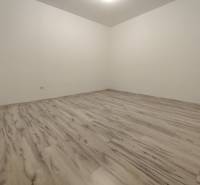 An empty room with wood-decor flooring in a 2-room apartment.