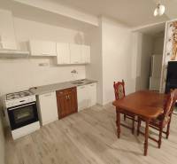 Kitchen in a 2-room apartment with a dining table, floor with wooden decor.