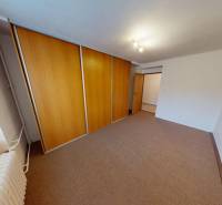 A room in a 2-bedroom apartment with a large built-in wardrobe and carpet on the floor.