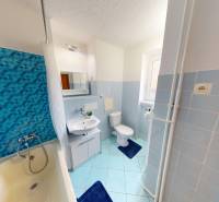 A bathroom with a bathtub and blue tiles in a 2-room apartment with a sink and a mirror.