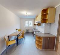 A kitchen in a 2-room apartment with a kitchen unit and a table with yellow chairs.