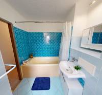 A bathroom in a 2-room apartment with colorful tiles and a bathtub.