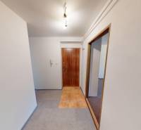A hallway in a 2-room apartment with tiles and doors with a wooden decor.