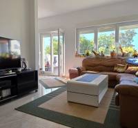 Living room with a brown leather sofa and decorative pillows in a three-room apartment.