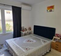 A bedroom with a bed in a 3-room apartment, white walls, and a window with curtains.