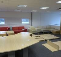 A commercial space with sofas, tables, and disassembled furniture on a dark floor.