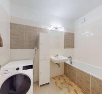 A bathroom in a 3-room apartment with a bathtub, sink, and washing machine.