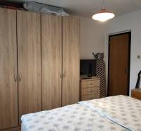 A bedroom with dark furniture, a television, and a bed, typical for a 3-room apartment.