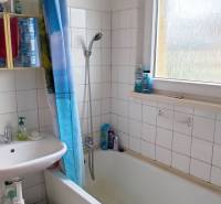 A bathroom in a 3-room apartment with a shower bath, curtain, and sink.