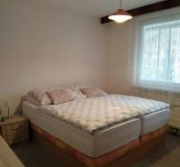 A bedroom in a 3-room apartment with a bed, a window, and wooden furniture.