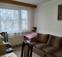 Living room in a 3-room apartment with a sofa, wooden decor furniture, lace curtains.