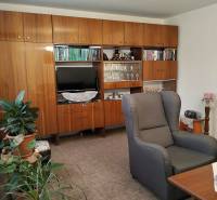 Living room of a 3-room apartment with carpet flooring, a large cabinet, and a comfortable armchair.