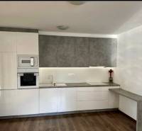 A kitchen in a 3-room apartment with white cabinets and a wood-patterned floor.