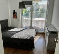 Bedroom in a 3-room apartment with a bed, window with blinds, and flooring with a wooden decor.