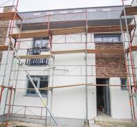 A family house in Nové Zámky with scaffolding and brick cladding during facade renovation.
