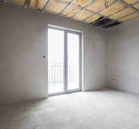 Empty room with a large window and an unfinished ceiling in a family house.
