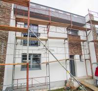A family house in Nové Zámky during renovation with scaffolding and brick detail on the facade.