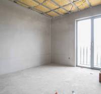 Empty room in a family house with plastered walls and large balcony doors.