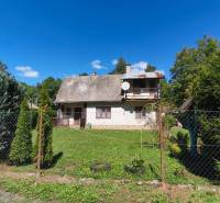 A cottage in Dolné Strháre with a garden, surrounded by greenery and a blue sky.