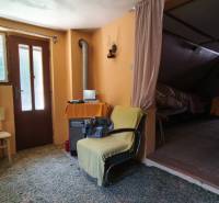 The interior of a cabin with wooden doors, a spiral stove, and comfortable armchairs.