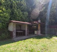 A garden at the cottage in Dolné Strháre with a gazebo, lawn, and surrounded by trees.