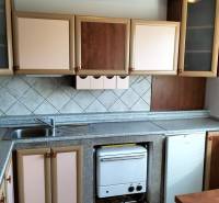 The kitchen of a one-room apartment with a wooden decor floor and a kitchen counter.