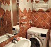 Bathroom with a washing machine, sink, and tiled walls in a studio apartment.