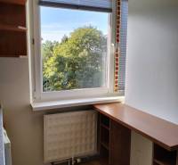 A small work corner with a desk, a floor with a wooden decor, and a view of greenery.